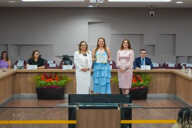 A imagem mostra o palco do plenário do TRE-RN e parte da plateia, com todos de pé, em posição de...