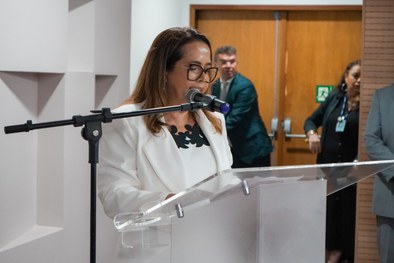 A imagem mostra o palco do plenário do TRE-RN e parte da plateia, com todos de pé, em posição de...