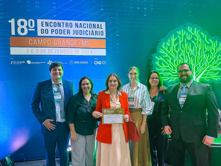 A foto mostra dois homens e quatro mulheres posando para uma foto. Os homens estão nas duas extr...